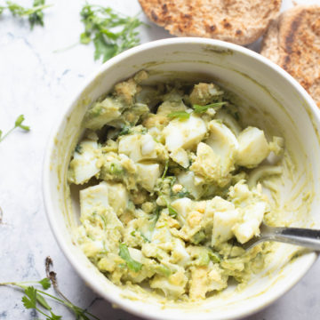 Bowl of avocado egg salad with brown bread on side