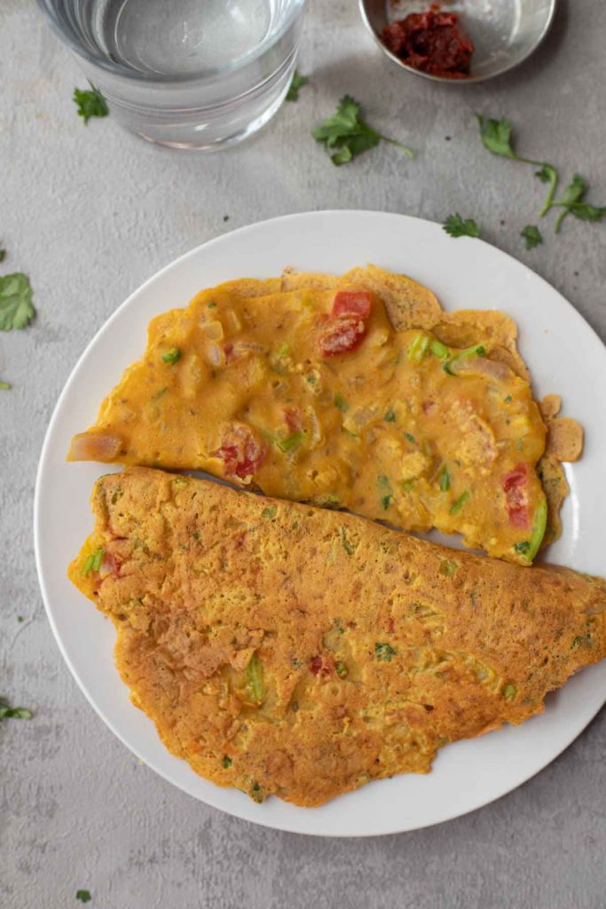 2 vegan chickpea flour omelette served with a pickle and a glass of water.