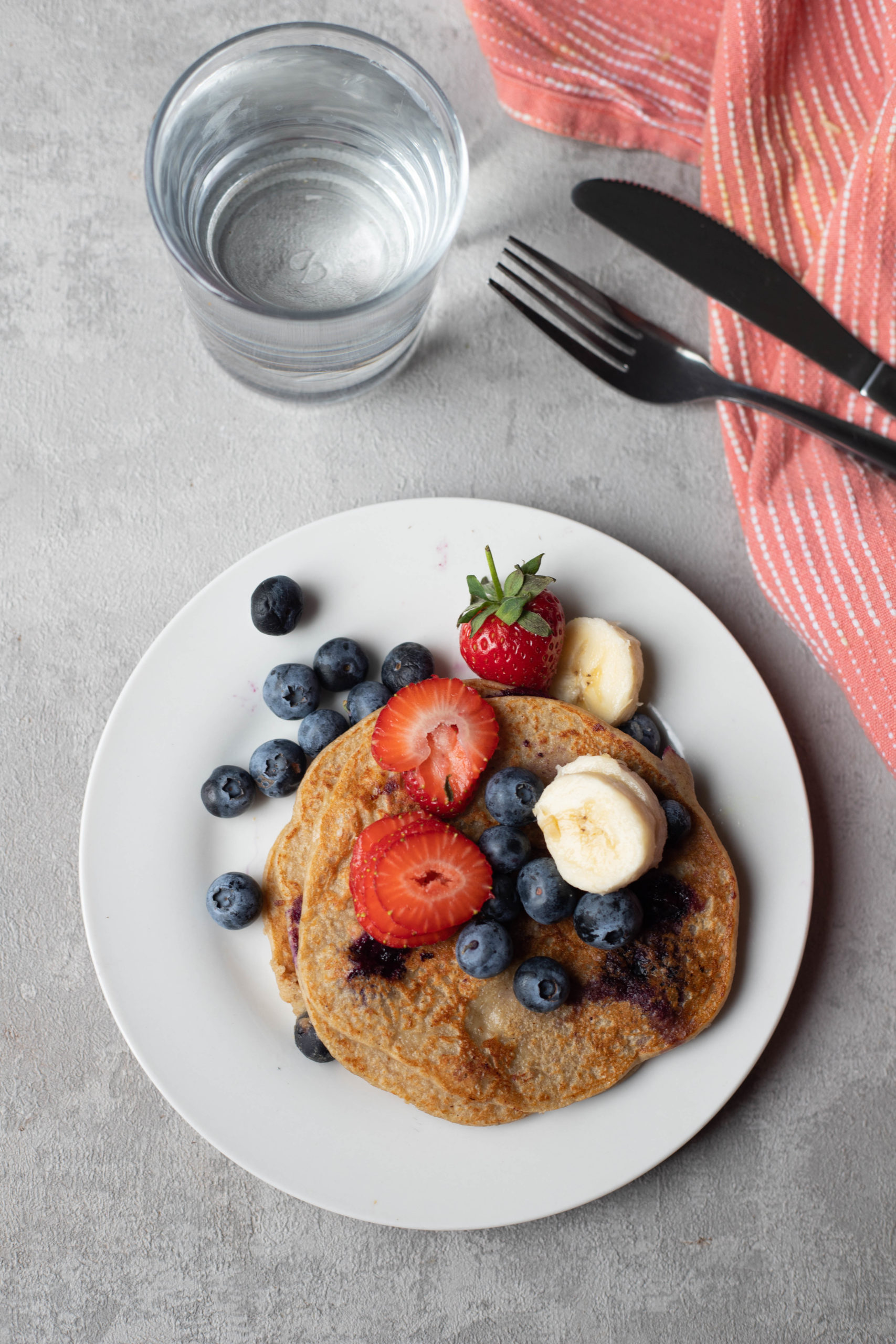 pancakes served with fruit and water