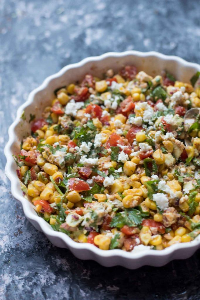 Mexican street corn salad served in a white plate with silver spoon