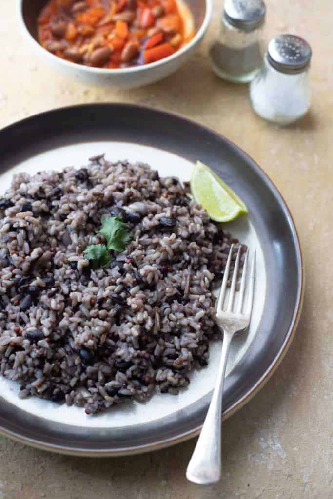 instant pot brown rice and beans served with a bowl of curry, salt and pepper in the background