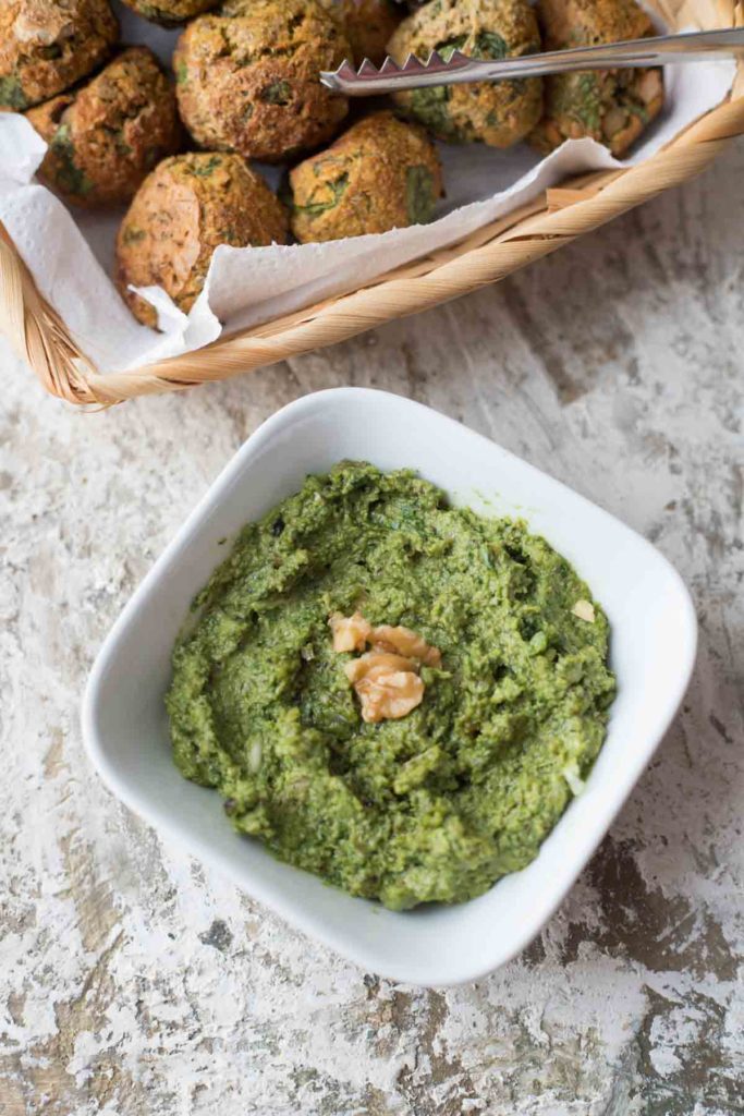 A bowl of low-fat basil pesto with spinach lentil balls in the background