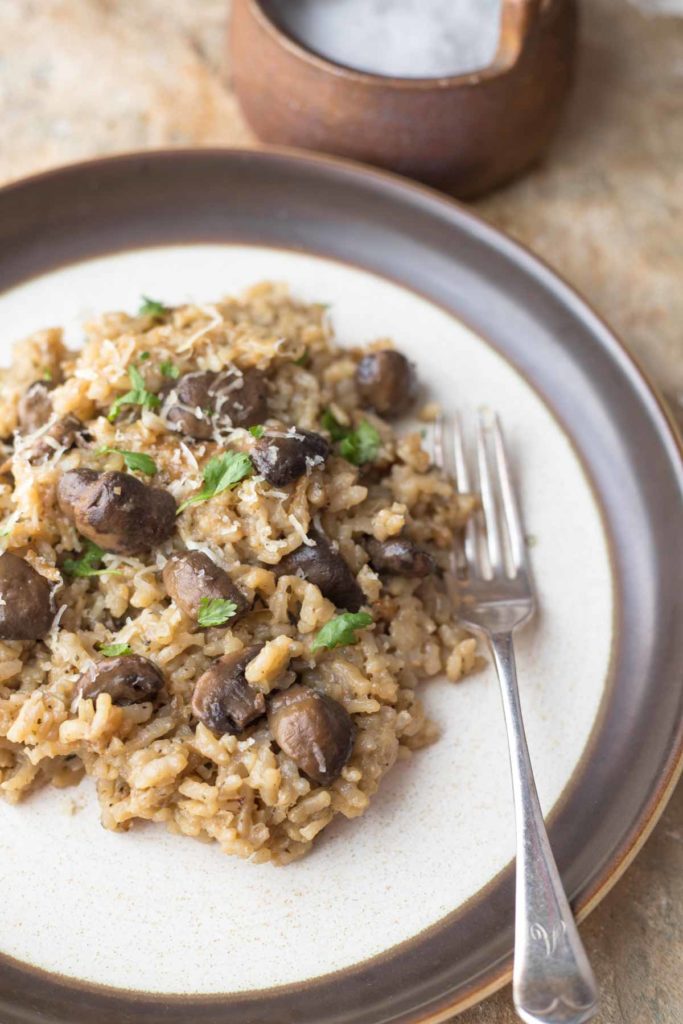 healthy mushroom risotto served on a plate with silver fork