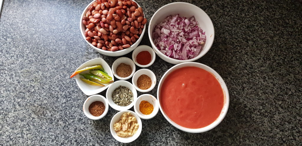 Ingredients to make instant pot Rajma Masala - beans,chopped onions. tomato puree, green chilli, spice powders like cumin, coriander,red chilli, turmeric