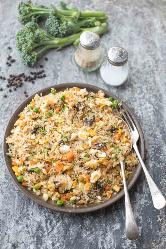 a plate of healthy fried rice with salt and pepper in the background