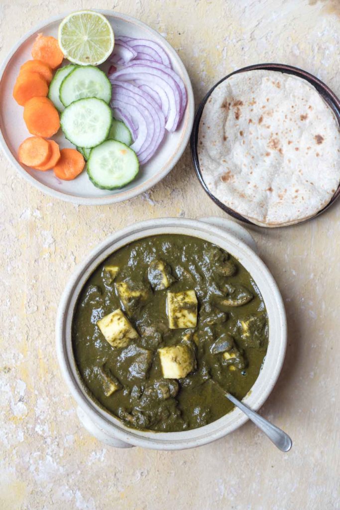 mushroom palak paneer served in a white bowl, rotis, salad