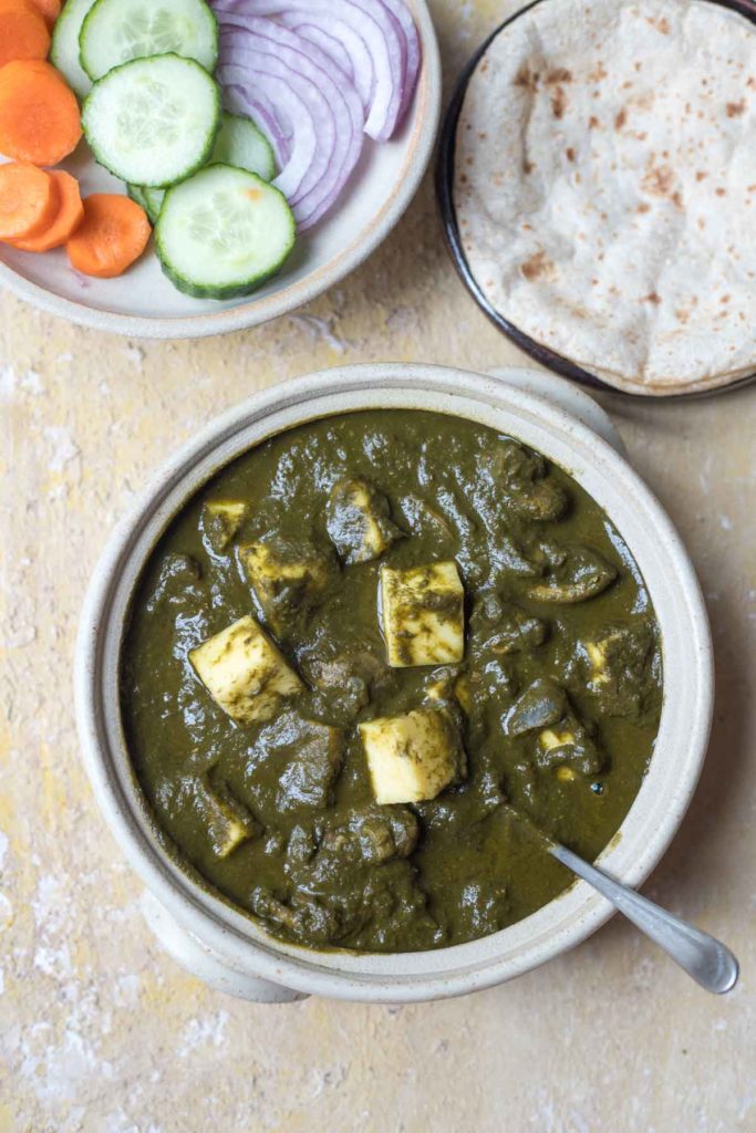 mushroom palak paneer served in a white bowl, rotis, salad