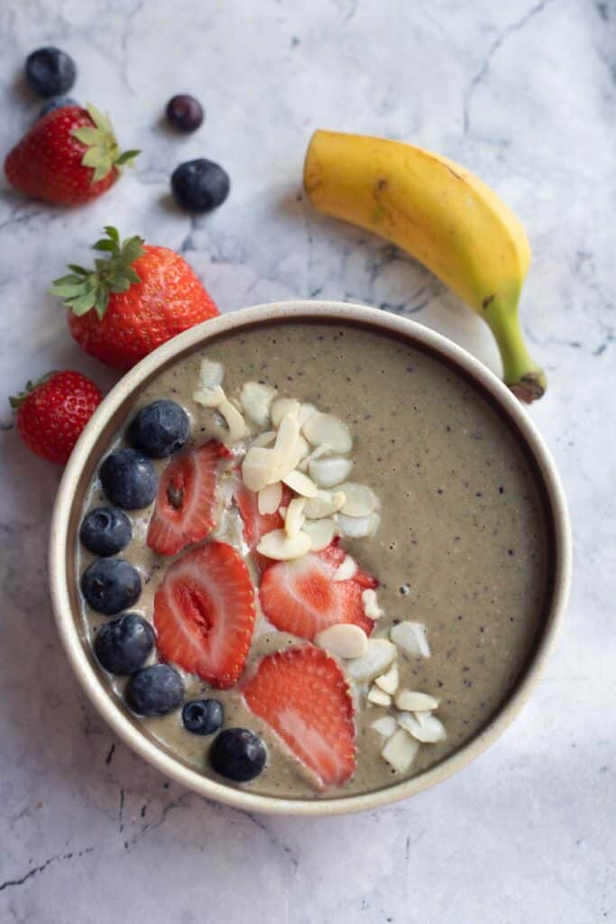 banana berry smoothie bowl topped with berries and almond flakes