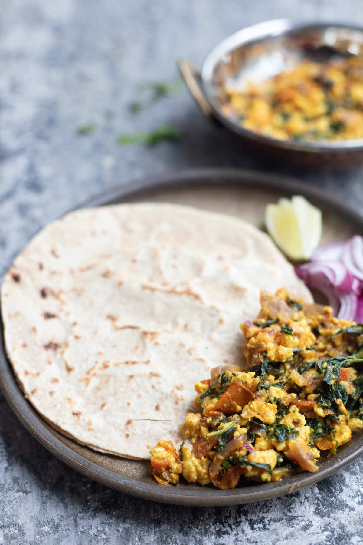 a plate of methi paneer bhurji , rotis , onion and lemon salad