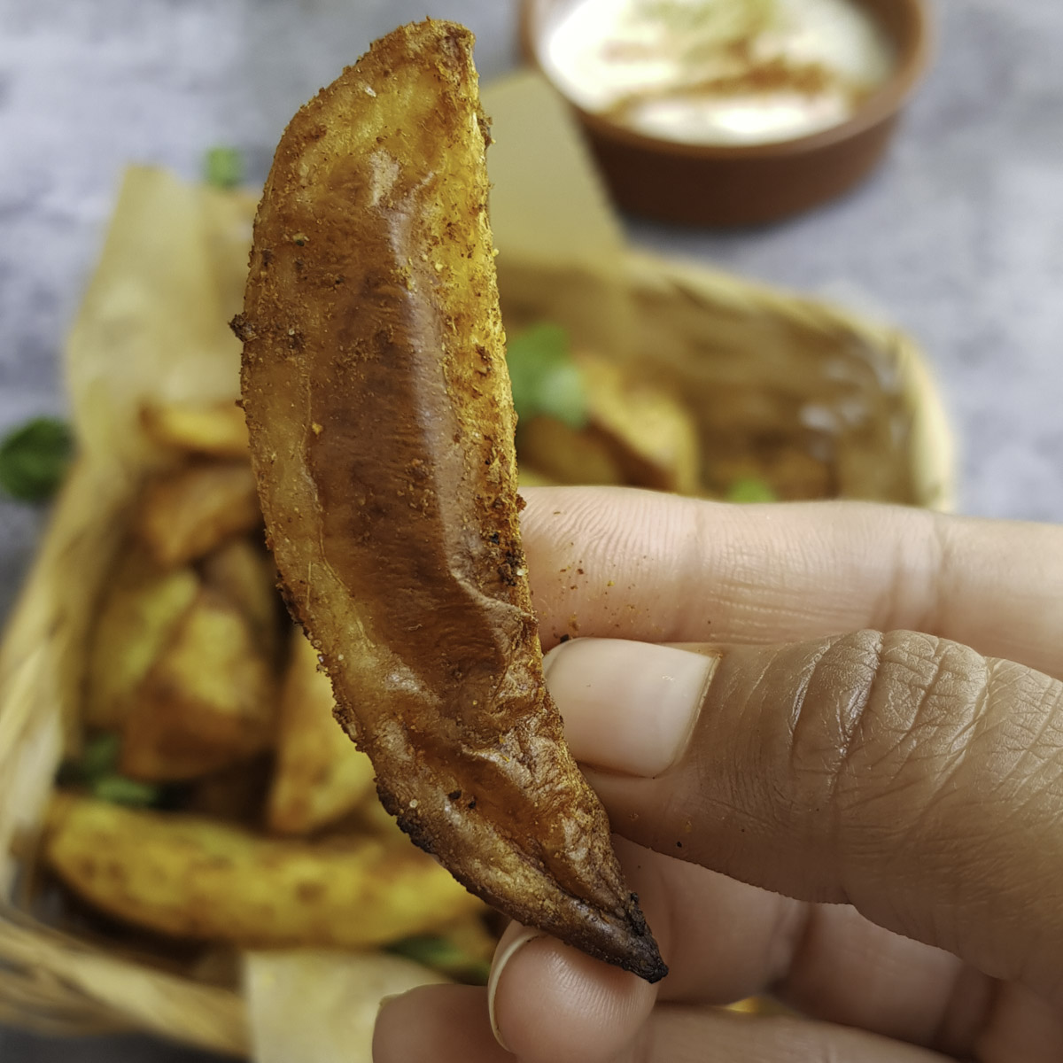 a hand holding crispy crusted potato wedge