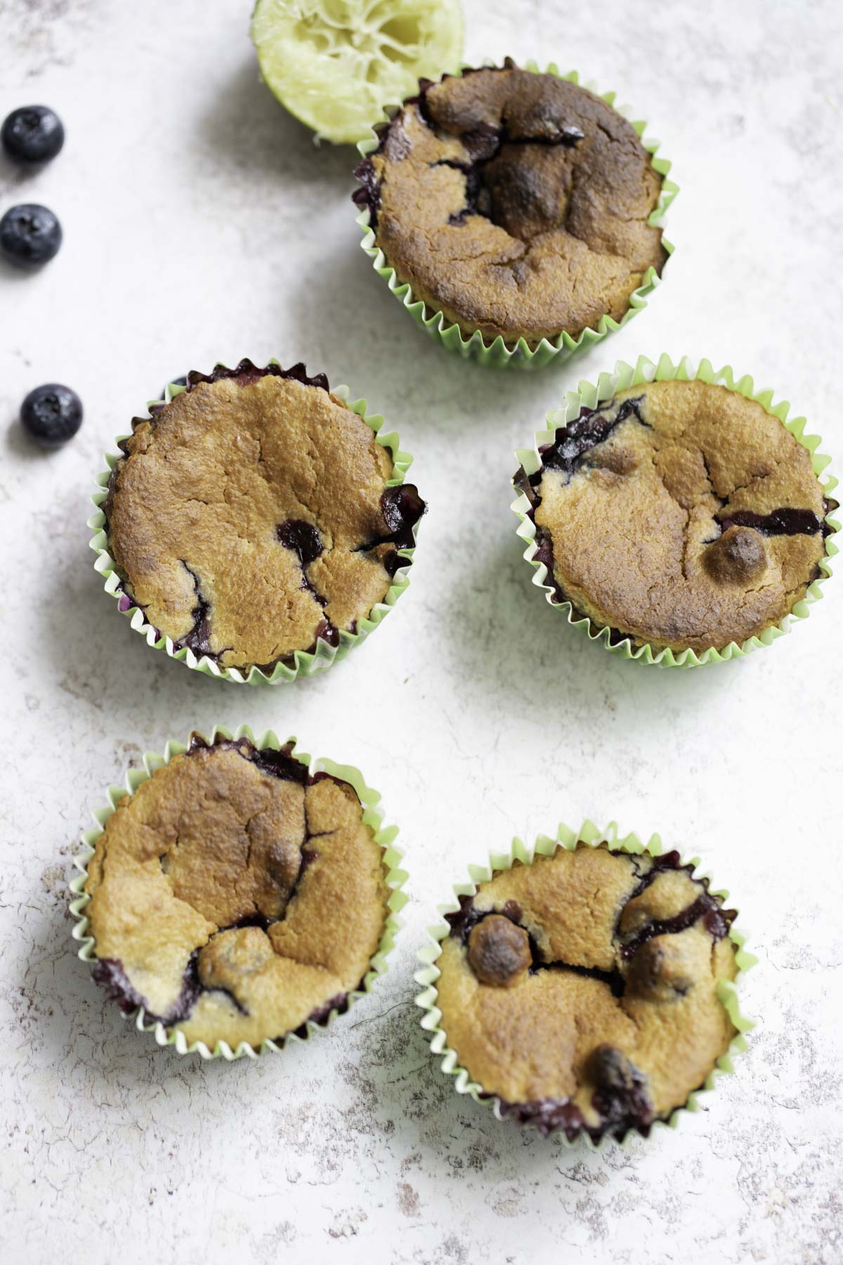 5 lemon blueberry oatmeal muffins with a lemon and blueberries in background