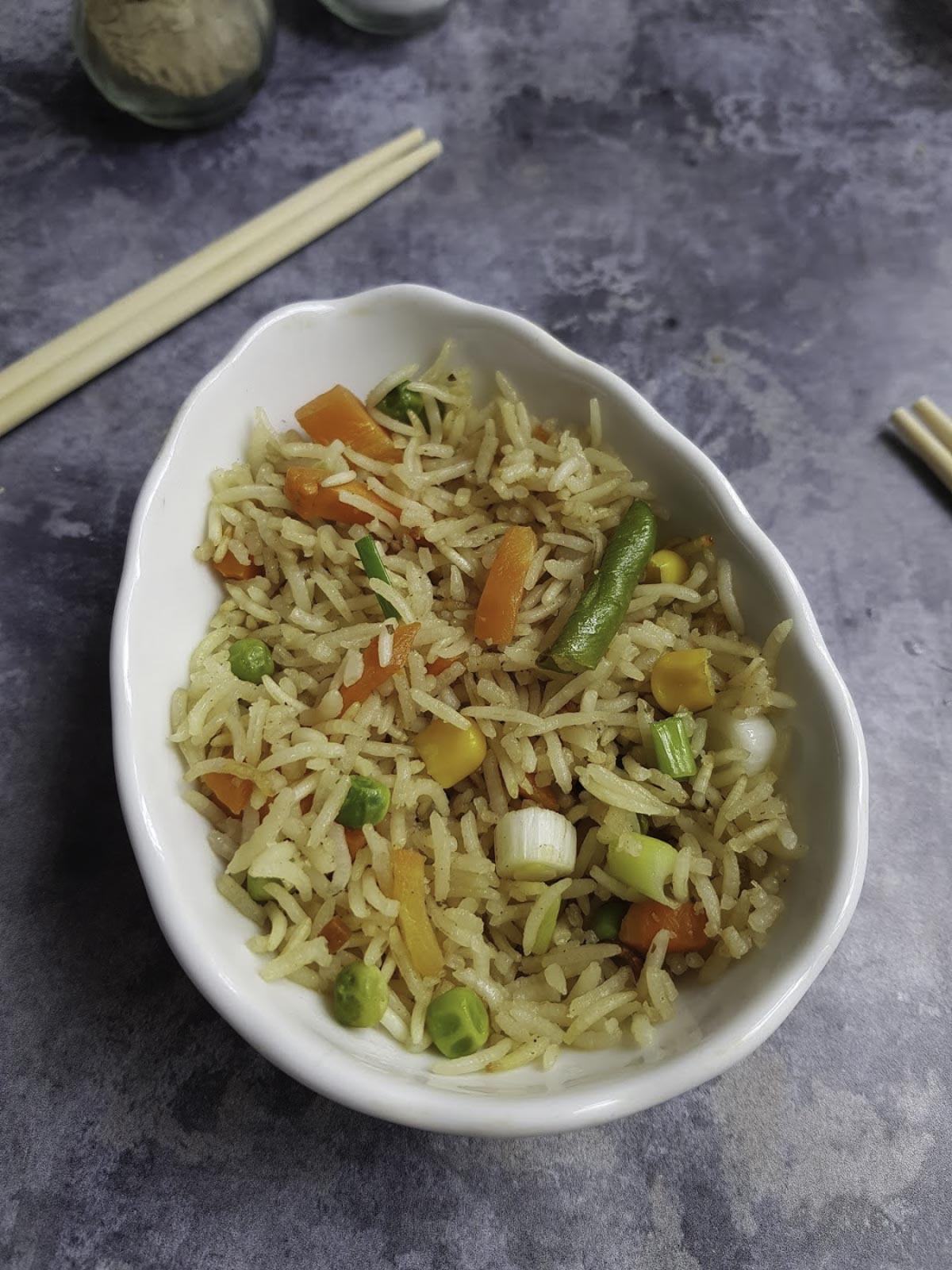 a small bowl of fried rice served with chopsticks in the background