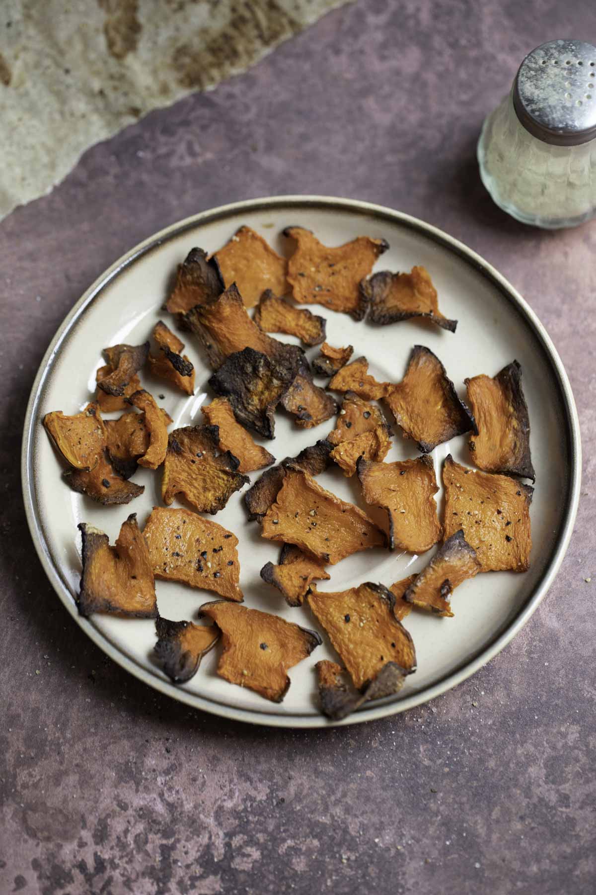 a plate of pumpkin chips with pepper in the background