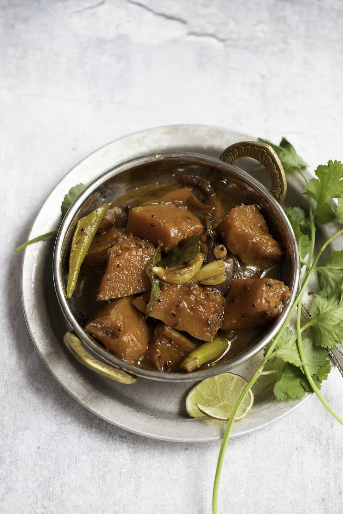 gummadikaya pulusu served in a kadai with coriander leaves on the side for decor