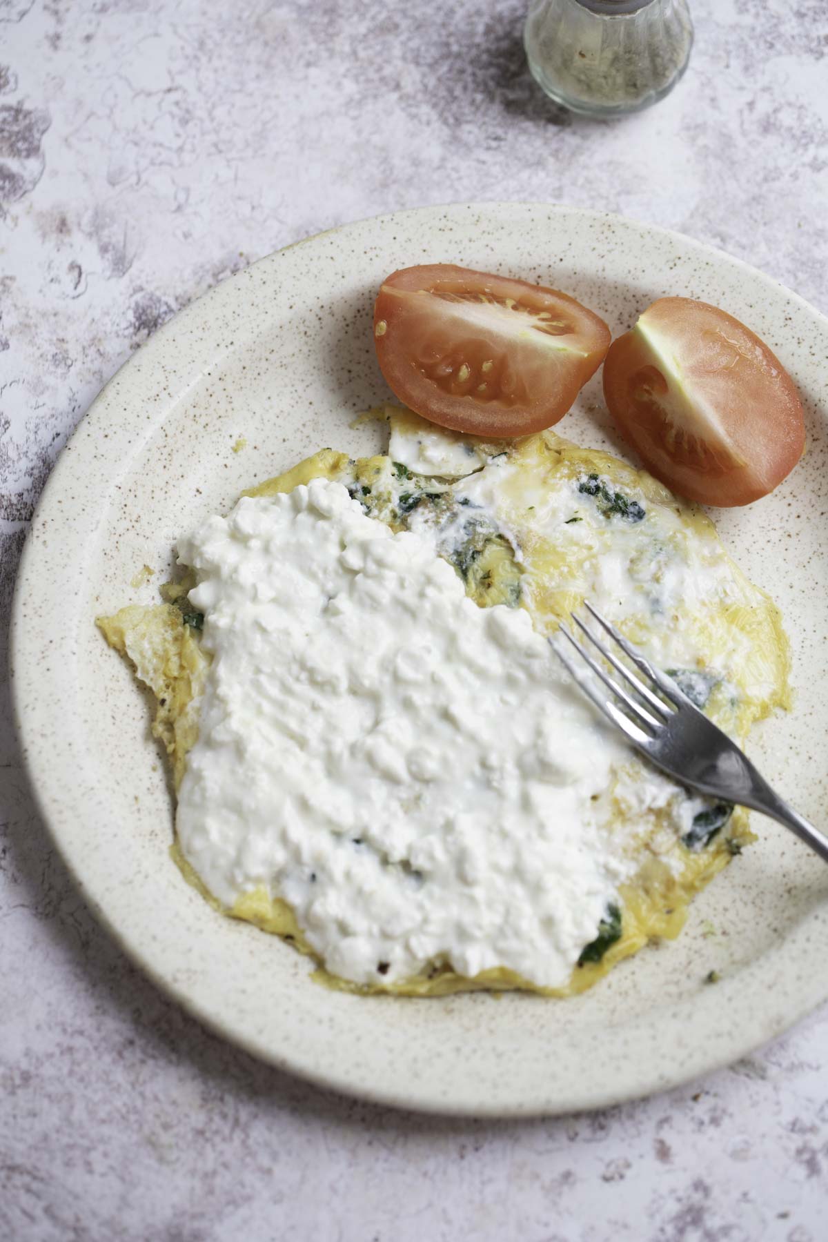 cottage cheese spread on spinach omelette, tomato slices on side