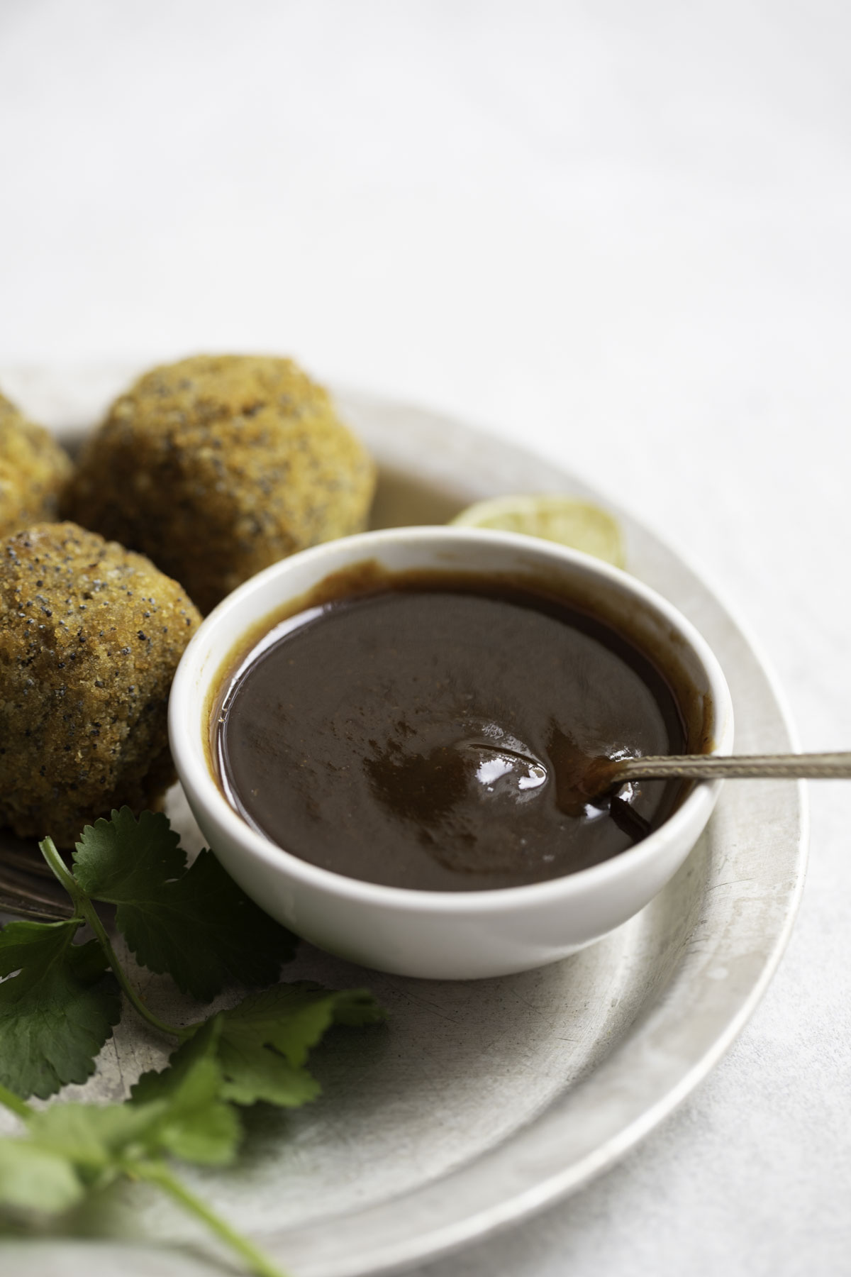 a bowl of tamarind sauce with spoon, paneer balls 